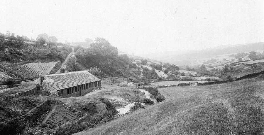 The grinding room at Wolf Wheel, probably the largest in the valley (undated). The footbridge marks the cross-valley route from Dore to Bradfield, which climbs the steep bank behind the building. Note also the cultivated land on the slopes nearby. From the KK collection.