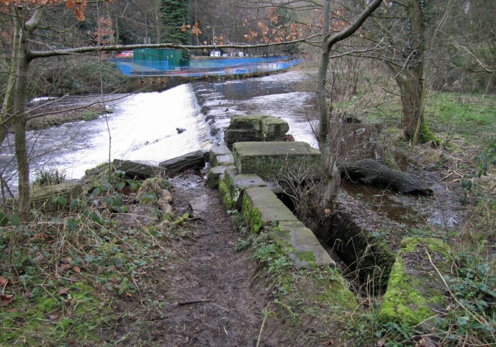 The long weir at Hollins Bridge Mill, with what may be the remains of the intake / shuttle for the waterwheel. Photo: Sue Shaw, February 2014.